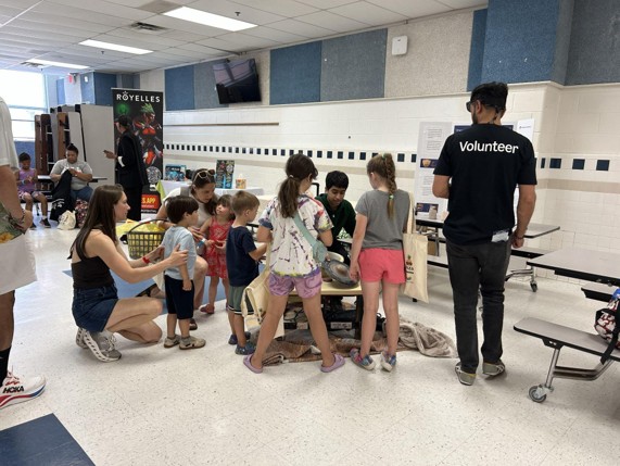 Students gathered around a potter's wheel during a workshop